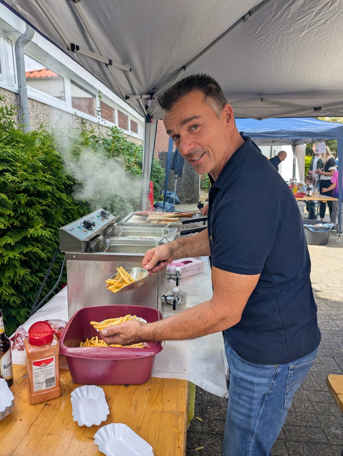 Das Bild zeigt Andre beim Ausgeben einer Portion Pommes